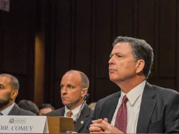 Former FBI Director James Comey testifies in front of the Senate Intelligence Committee in the Hart Senate Office building in 2017 (Image via Shutterstock.com)