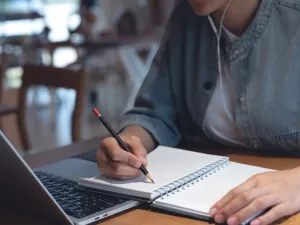 Student seated at laptop taking notes.