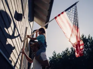 Father and daughter hang an American flag outside their home