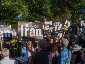 Protesters gather with Palestinian flags and "Hands Off Iran" signs during a demonstration near the US Embassy in London.