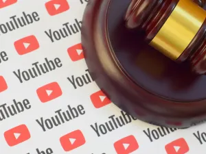 Youtube paper logo lies with wooden judge gavel. (Image via Shutterstock.com)