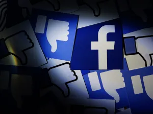 Close up Facebook logo surrounded by thumbs down icons. (Image via Shutterstock.com)