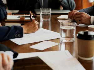 hands of people using phones and writing during a board meeting