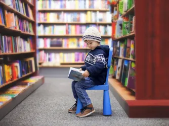 small boy reading a book in a library