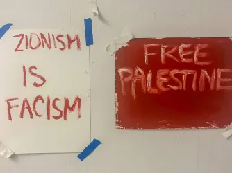 Two paper signs posted on a door, one reading "Free Palestine" and the other "Zionism is Fascism"