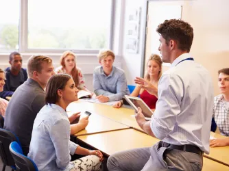 Teacher With College Students Giving Lesson In Classroom