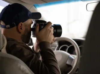 Private investigator taking photos in his car