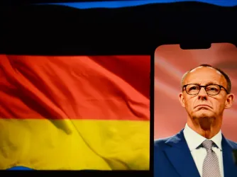 German Chancellor Friedrich Merz on a phone screen with German flag in the background