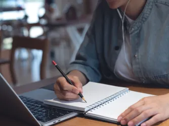 student seated at laptop taking notes