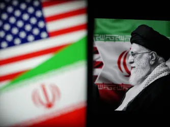 Iranian Supreme Leader Ayatollah Ali Khamenei next to Iranian and US flags displayed on screens