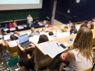 Students sit in lecture hall as professor speaks