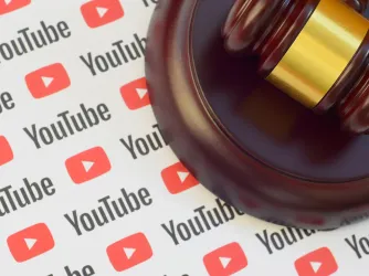 Youtube paper logo lies with wooden judge gavel. (Image via Shutterstock.com)