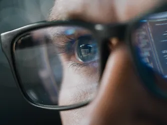 reflection of AI output in man's glasses as he reads