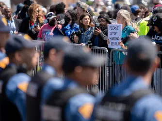 An anti-ICE protesters holds a sign opposing a line of New Jersey State Police during a rally in support of Immigration and Customs Enforcement outside Delaney Hall on May 30 2026, in Newark, New Jersey. (Image via Imagn / USAToday)