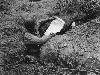 soldier in foxhole reading paper