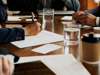 hands of people using phones and writing during a board meeting