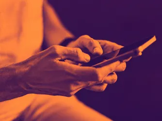 image of a woman's hands as she posts on social media on her phone, in duotone