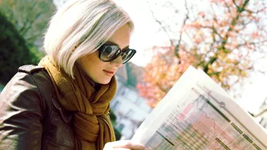 Woman reading a newspaper (image via Shutterstock.com)