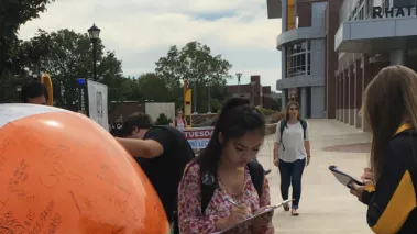 Students use sharpies to write statements on a giant beach ball at Wichita State University
