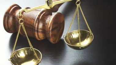 Photograph of a gavel and scales of justice on a black desk