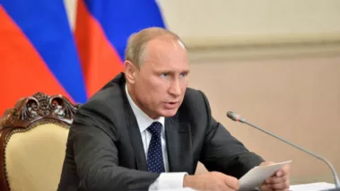 Russian president Vladimir Putin sitting at a desk delivering a speech