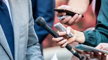 Journalists with microphones interviewing formal dressed politician or businessman.