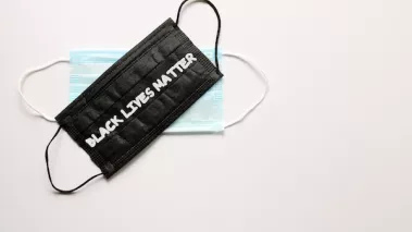 Black and white face protective masks are on white background. The text: Black lives matter is on black mask. Concept of protest against racism and violence