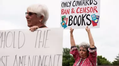 Opponents to a proposed library policy in Central Bucks School District holding up signs comparing the policy to censorship and book banning
