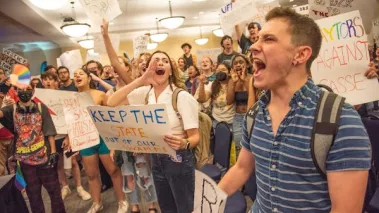 Student protestors wave signs and chant ‚hey hey, ho ho, Ben Sasse has got to go.