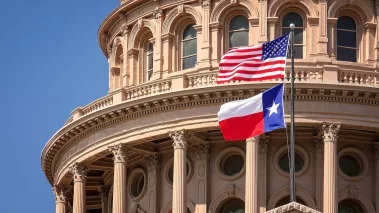 American and Texas state flags flying on the dome of the Texas State Capitol building in Austin