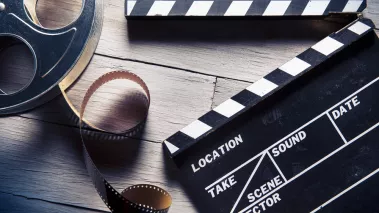 Movie clapper and film reel on a wooden background 