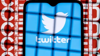 Twitter social network logo on the smartphone screen behind the bars on the background with the inscription censored