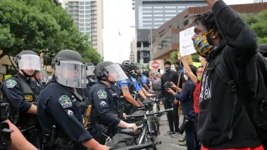 A Black, male activist protesting the death of George Floyd and Mike Ramos, a Black Hispanic man killed by Austin police, confronts white officers blocking a street.
