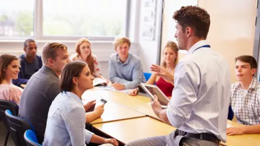 Teacher With College Students Giving Lesson In Classroom