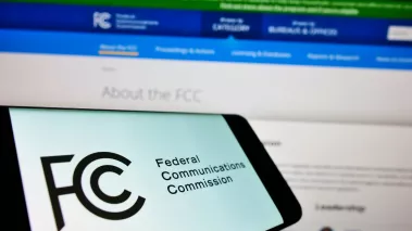 Mobile phone with seal of US agency Federal Communications Commission FCC on screen in front of web page
