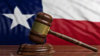 Judge or auction gavel on Texas US of America waving flag background