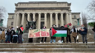 ro-Palestinian students holding "Money Talks Strike Tuition" banner and a Palestinian flag at a protest on the Columbia University campus