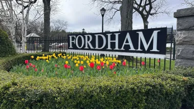 Fordham University entrance sign in the spring with tulips in bloom