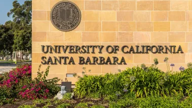 Goleta, California, USA - August 7, 2018: Closeup of name and seal of UCSB at Monumental brown stone Henley Gate. Plenty of grass and flowers up front.