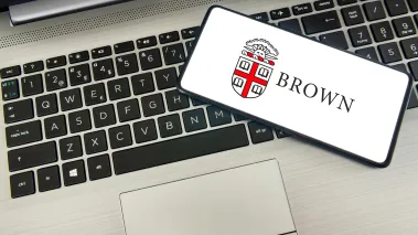 A smartphone laying on a laptop with the Brown University logo on it