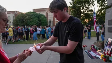 Kalib Magana helps light a candle during a vigil in honor of Charlie Kirk following his death on Wednesday, Sep. 10, 2025 at the University of Oklahoma in Norman, Oklahoma. Kirk, founder of Turning Point USA, was killed by a gunshot wound to the neck while speaking at Utah Valley University.