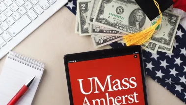University of Massachusetts Amherst logo displayed on a tablet next to a keyboard and money