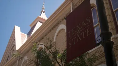 Texas State University banner and Old Main building in San Marcos