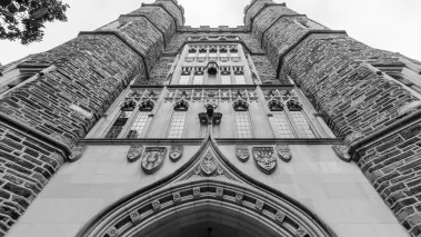 Black and white photograph of Duke University stone campus building with the perspective looking up to the sky, so the building appears imposing.