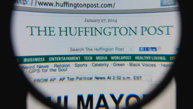 Photo of The Huffington Post homepage on a monitor screen through a magnifying glass