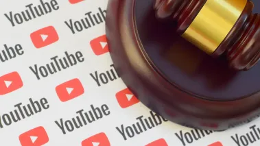 Youtube paper logo lies with wooden judge gavel. (Image via Shutterstock.com)