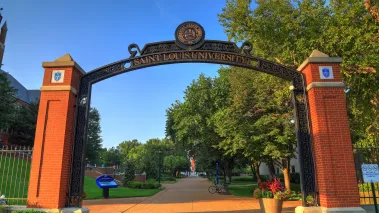 Saint Louis University entrance with school name on a cast iron arch over the sidewalk (Image via Shutterstock.com)