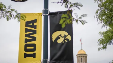University of Iowa banner with logo on campus with the Old Capitol in background.