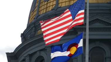 Colorado state capitol with US and Colorado flags in foreground (Image via Shutterstock.com)