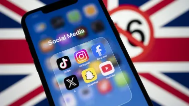 Social media app icons displayed on a smartphone screen in front of a blurred Union Jack flag (Image via Shutterstock.com)